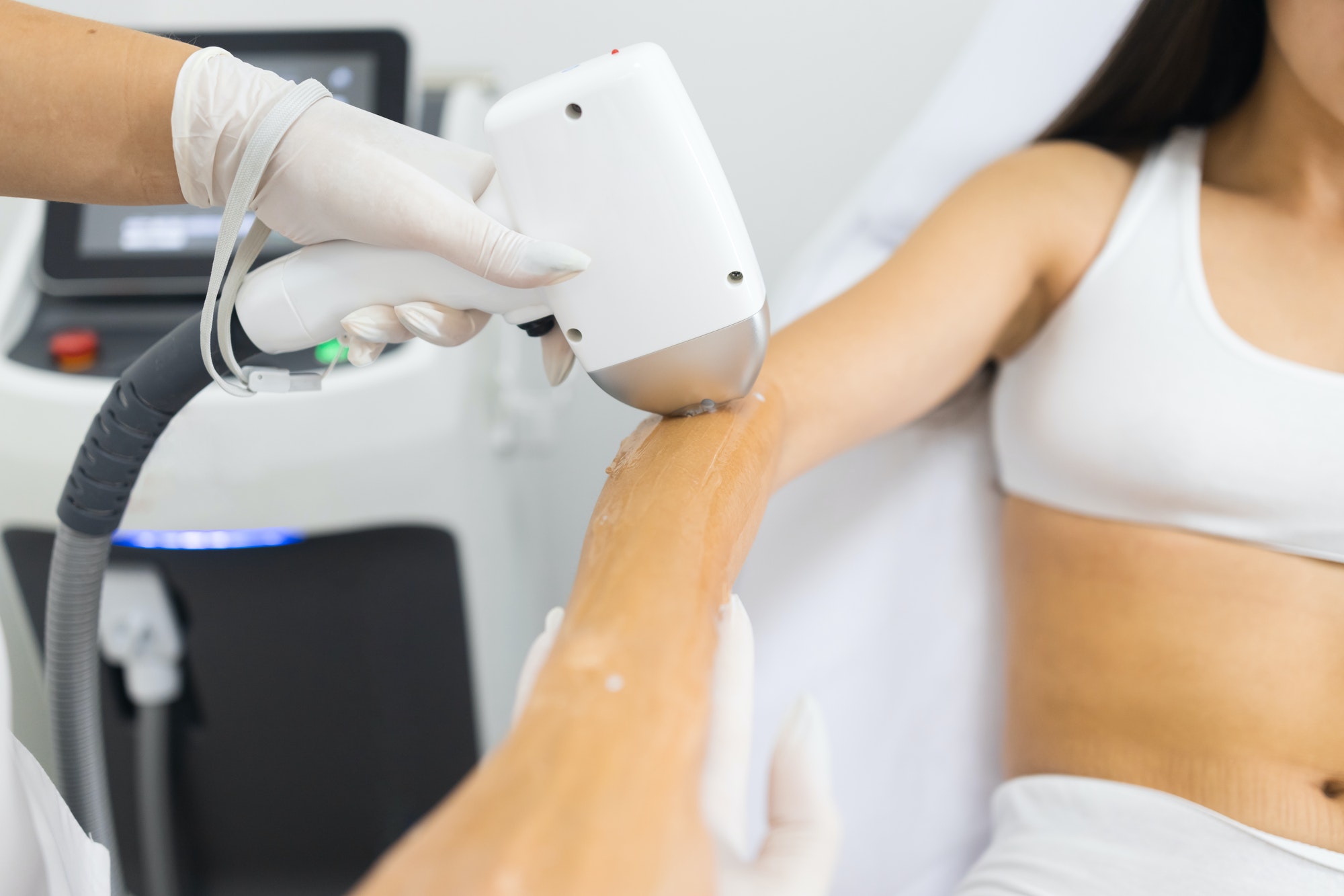 Doctor makes to brunette woman in white underwear a laser hair removal procedure